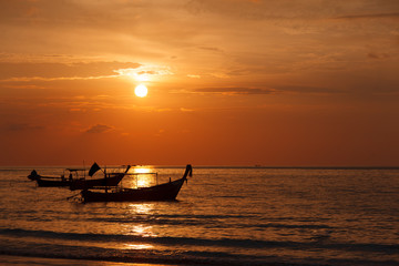 Two longtail boat silhouette at sunset in Phuket, Thailand. Tropic travel destination. Meditative and simple seascape with copy space.