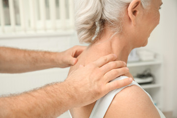 Elderly woman getting shoulder massage at physical therapy office