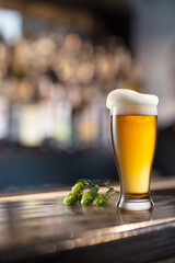 Glass of beer on wooden table and blurred background.