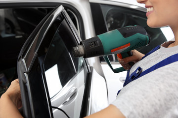 Female worker tinting car window