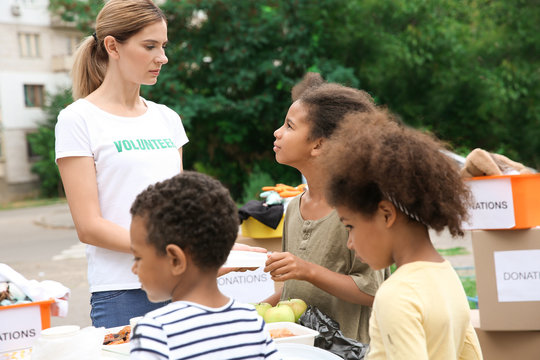 Volunteer sharing food with poor African children outdoors