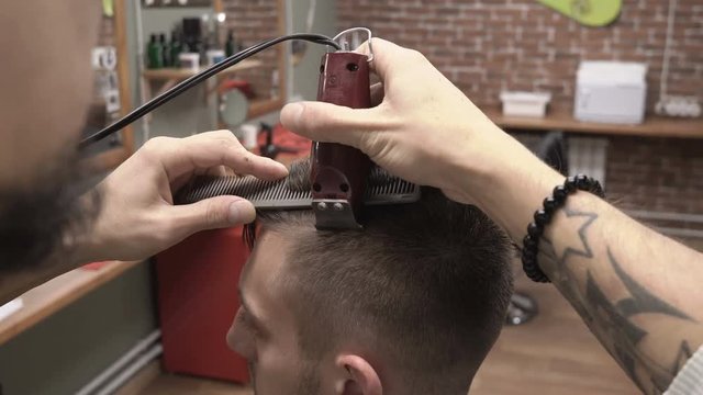 Barber cuts the parting of the hair with clipper haircuter close-up 4k.