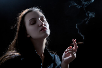 Obraz premium beautiful woman smoking cigarette on black background