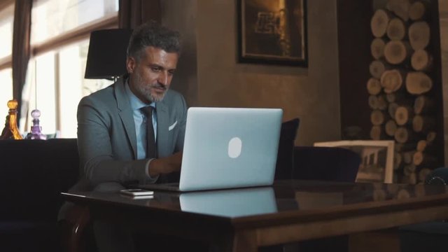 Mature businessman with laptop in a hotel lobby.