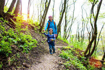 Obraz premium The boy and his mother are walking through the woods.