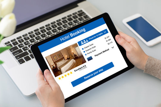 female hands holding tablet with app hotel booking on screen