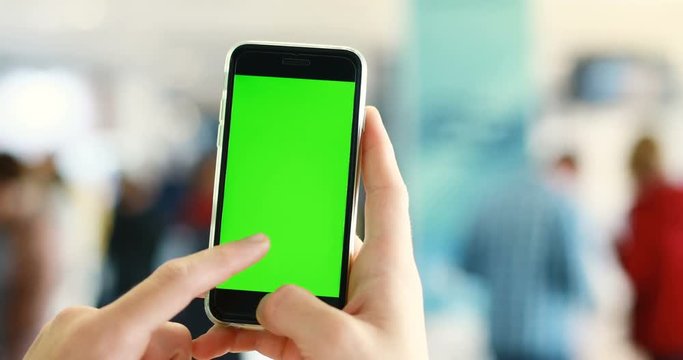 Man hand holding using green screen smart phone chromakey blank display public space people app internet surfing tapping pointing finger touchscreen mockup browser connection male digital closeup