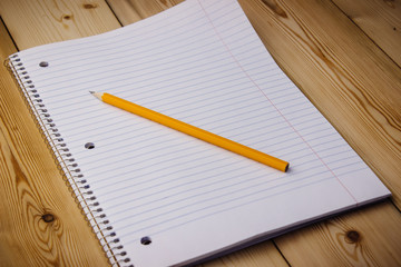 notebook with black pencil on  wooden background