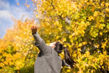 girl in the park throws autumn leaves