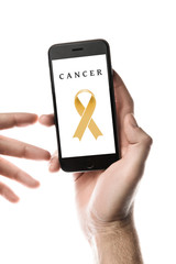 Hand holding smartphone, blank screen with gold ribbon isolated on white background. World Cancer Day. Childhood cancer concept