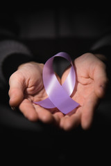 healthcare concept - child hands holding cancer awareness ribbon