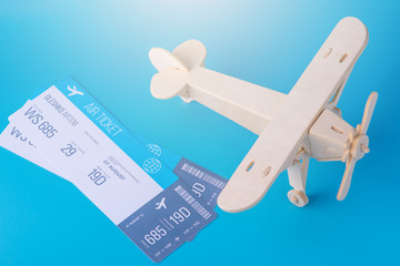 Wooden toy airplane and tickets on a background of blue sky with paper clouds. Concept travel and airlines