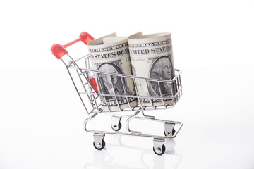 Shopping cart with dollar money isolated on white background.