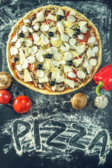 Homemade large vegetarian pizza with ingredients ready to bake on a dark table with text
