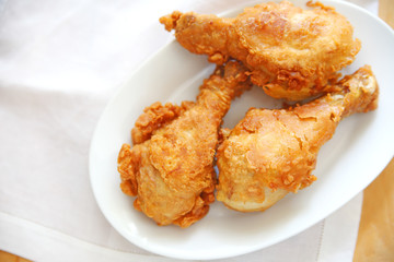 Three fried chicken legs on a dish with a white napkin and copy space