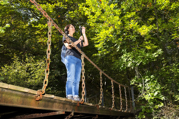 Naklejka na ściany i meble trekking and hiking , woman in wooden bridge over river