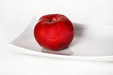 Red apple on a white plate.