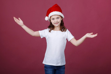 portrait of a smiling little girl in Santa hat on red background in Studio. Emotions. Christmas