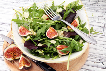 Autumn salad of arugula, figs in a white earthenware plate.