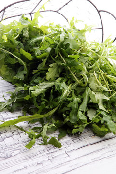 Fresh green arugula in basket on wooden table. Arugula is rich in vitamins and trace elements.