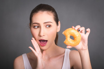 Beautiful Woman eating donuts. Junk food, Slimming, weight loss.  People with sweets, dessert. Diet, dieting concept. Isolated on gray background