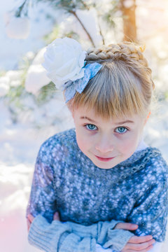 Winter fairy tale. Beautiful little girl is walking in a snowy forest