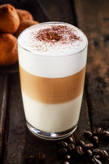 Glass of latte macchiato standing on wooden table