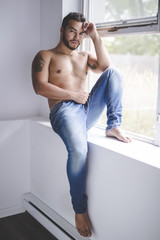 Fototapeta na wymiar Sexy fashion portrait of a hot male model in stylish jeans with muscular body