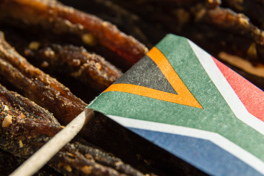 A Close Up Image Of A Small South African Flag On Top Of Slices Of Biltong (dry Meat) Which Is A Traditional South African Food Snack.