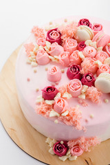 Pink glazed cake with cream flowers on white background