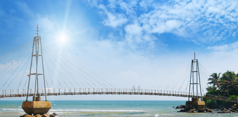 bridge to island, ocean and sun in blue sky