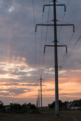 Power transmission line supports leaving the horizon on a sunset background. Concept of electricity.