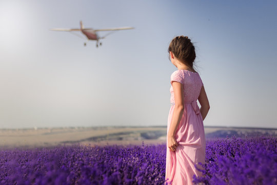 girl stands in lavender and looks at the plane
