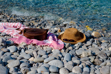 Straw hat, sunglasses, towel, bag on a background seascape with a pebble beach