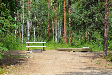 A campsite with a picnic table, fire ring and tent platform