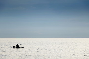 Fototapeta premium silhouette people boating canoe boat in sea on vacation time for relax at Teay Ngam Beach, Thailand. Blue tone look beautiful.