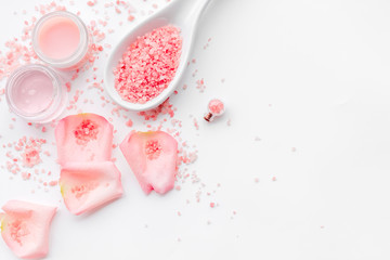 Rose bath salt in spoon near rose petals on white background top view copyspace