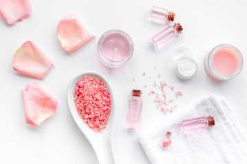 Spa products with rose oil. Cream, lotion and salt on white background top view copyspace
