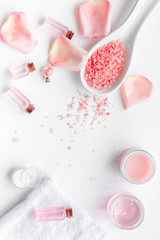 Spa products with rose oil. Cream, lotion and salt on white background top view copyspace