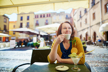 Girl drinking coffee and eating ice cream in Italian cafe