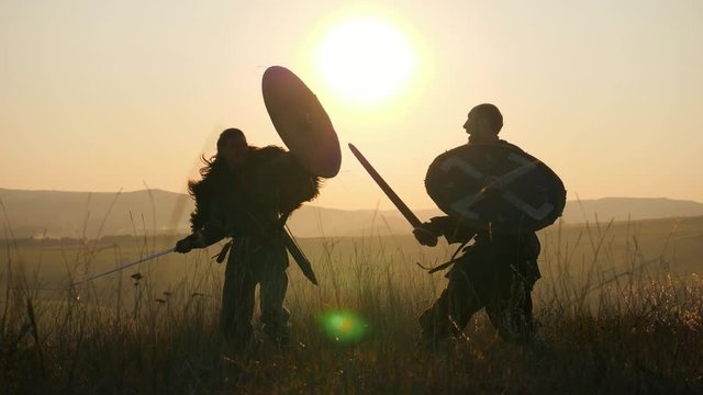 Silhouettes of warriors Viking are fighting with swords and shields. Contre-jour