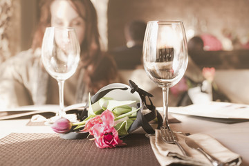 букет цветов на столике в ресторане рядом с бокалами и на фоне девушки читающей меню