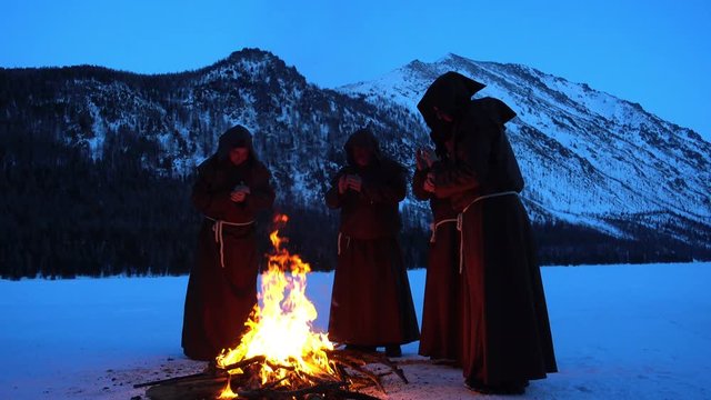 Four monks pray at the campfire in the mountains slowmotion