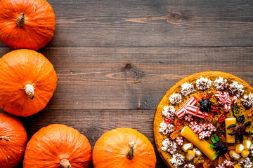 Homemade pie for halloween decorated gummy spiders among pumpkins on wooden background top view...