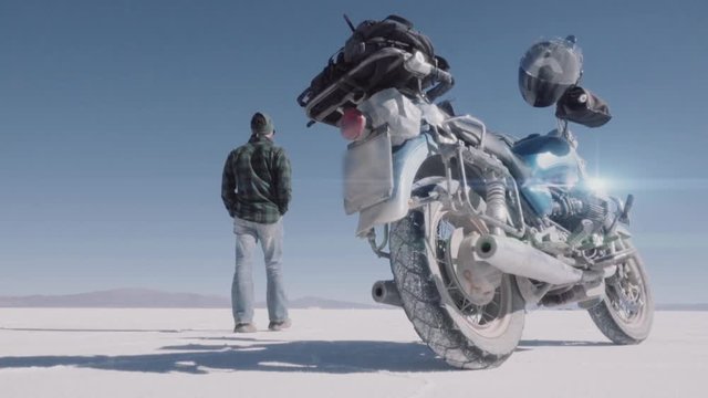 Male biker walks near the motorcycle Salt flats Uyuni,  Bolivia. Trip motorcycle adventure.