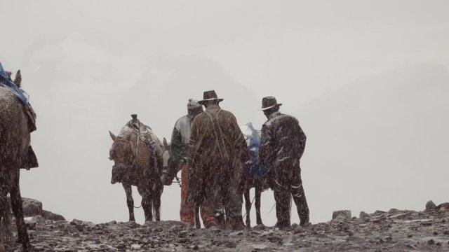 Peruvian muleteers talking during a snowfall near the Nevado Pastoruri. Slow motion