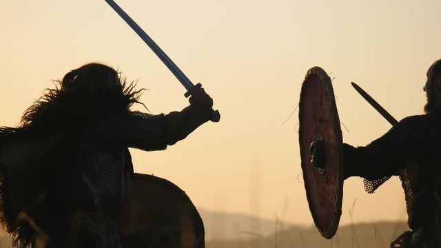 Silhouettes of warriors Viking are fighting with swords and shields. Contre-jour