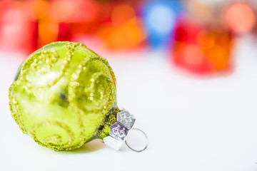 Close-up of green xmas ball with blurred colorful Christmas decor in background. Christmas and New Year concept with copy space. Christmas greeting card.