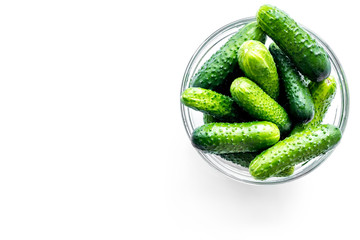 Fresh cucumbers in bowl on white background top view copyspace