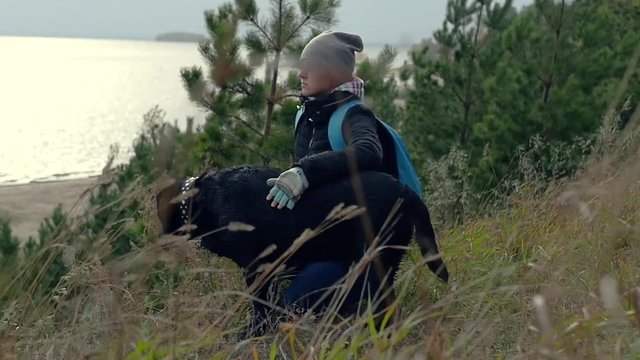 A young girl sits hugging with her dog, admiring the scenery. slowmotion, HD, 1920x1080